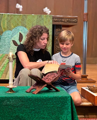 Adult helping a child read from a book at a church altar