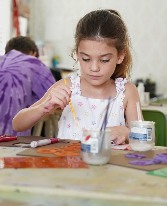 Child painting craft shapes at a table