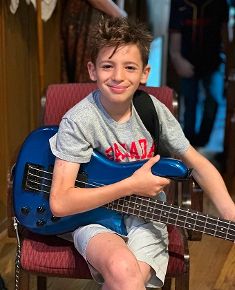 Child smiling while holding a blue electric guitar
