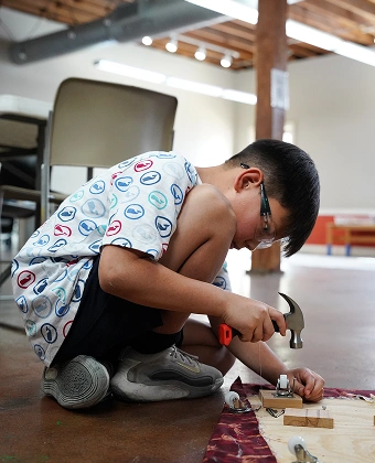 Child using a tool to build a small wooden project