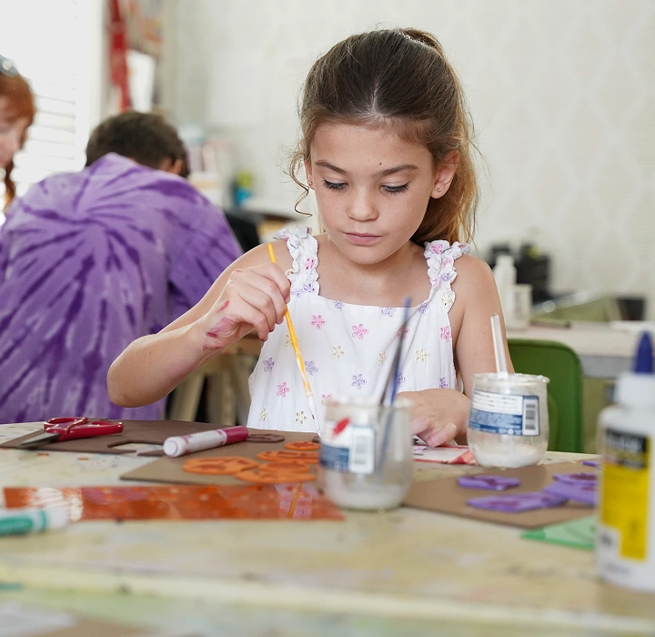 Child painting craft shapes at a table
