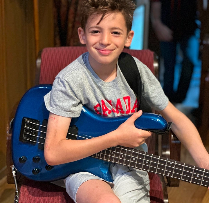 Child smiling while holding a blue electric guitar