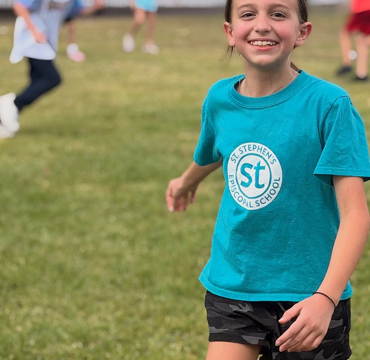 Smiling child running on a grassy field during outdoor play
