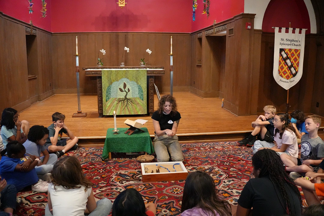 Teacher leading a group lesson with children seated around her in a church hall