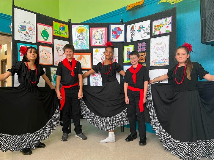 Children in black outfits with red accents posing in front of a colorful art display