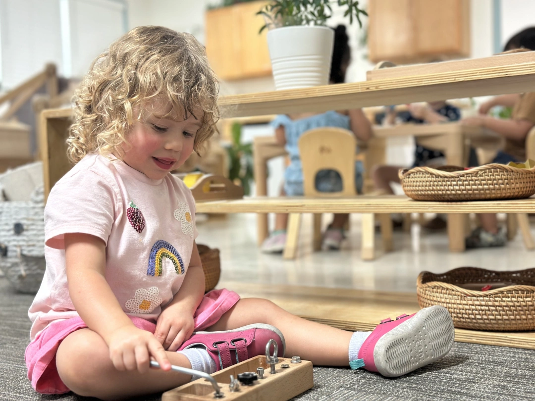 Child playing with a hands-on activity board on the classroom floor