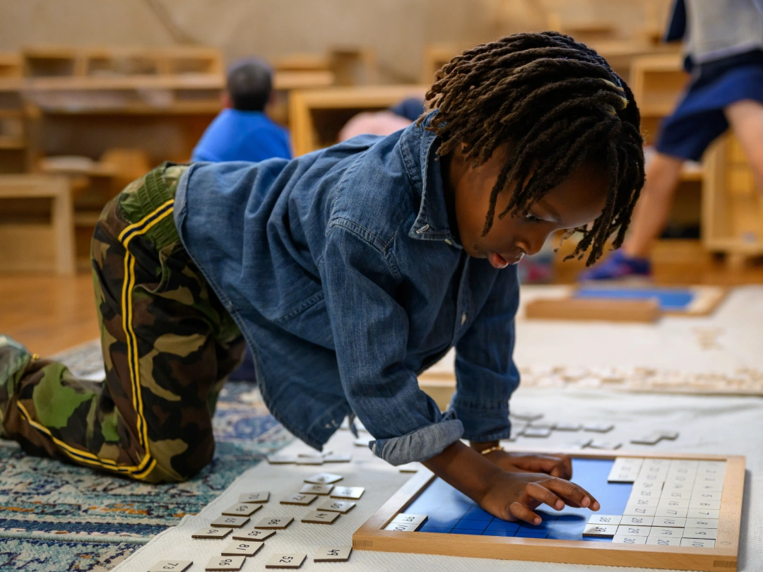 Child using a hands-on learning board on the classroom floor